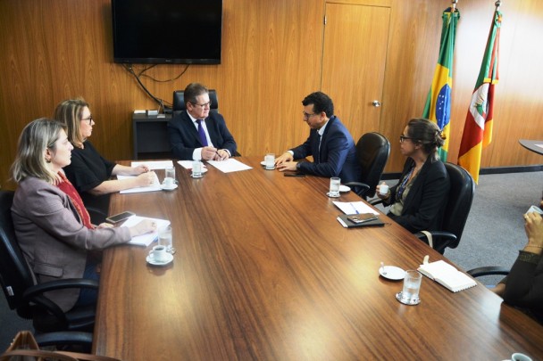 Mesa de reuniões do gabinete do vice-governador. Sentado à cabeceira, Ranolfo Vieira Júnior e ao seu lado o deputado estadual Jeferson Fernandes. Ao redor da mesa, a chefe de gabinete do vice e assessores. Ao fundo, à direita, bandeiras do Brasil e do RS.