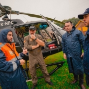 Quatro homens conversam ao lado de helicóptero da Polícia Civil do RS