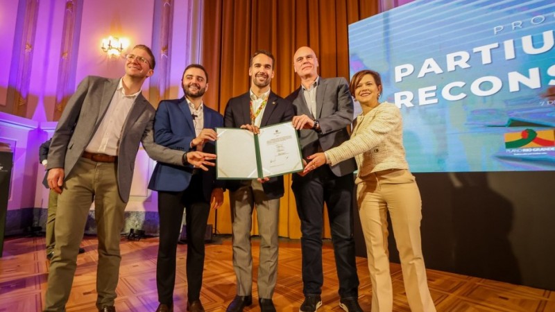 Cinco pessoas seguram documento assinado