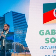 Gabriel atrás de um púlpito transparente falando durante a abertura do Décimo Segundo Cosud.