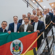 Comitiva que participou da missão pousa em uma escada, segurando a bandeira do Rio Grande do Sul.