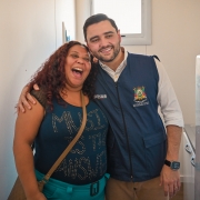 Gabriel Souza abraça uma mulher durante entrega de moradias temporárias. Ambos sorriem.
