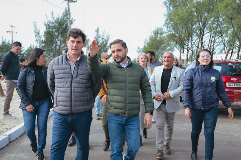 Há duas pessoas na frente e outras sete atrás deles. Todos de pé e caminhando. Um dos homens na frente está com o braço levantado.